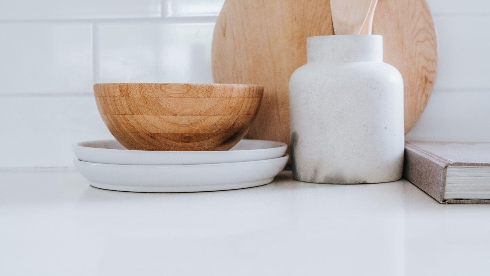 Encimera con tabla de madera, cuenco, tarro de cerámica y utensilios