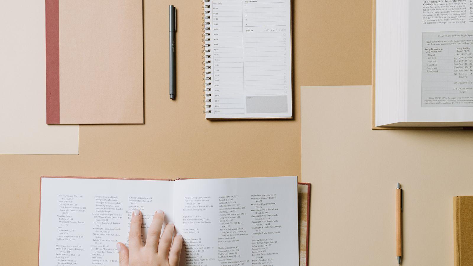 Escritorio con cuaderno, bolígrafo y libros sobre una mesa de madera
